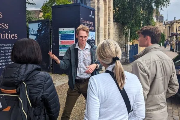 Rory, the tour guide, explains the history of Trinity College Oxford to a group of tourists.